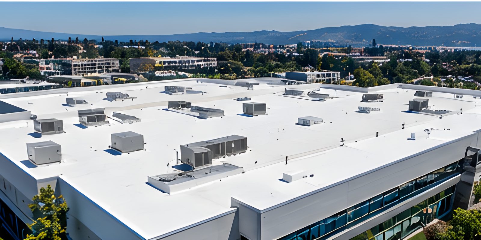 White membrane low-slope roof of a commercial building, Peninsula hills beyond.