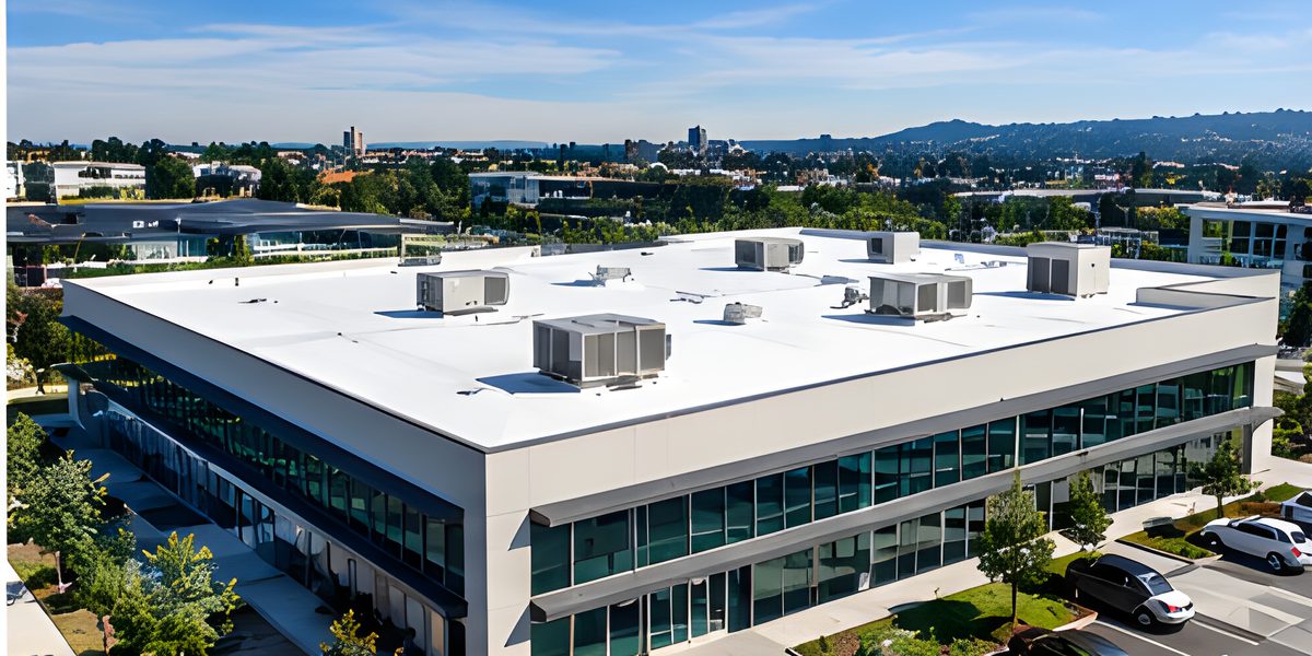 Flat white roof of an office building with rooftop units, the city beyond.